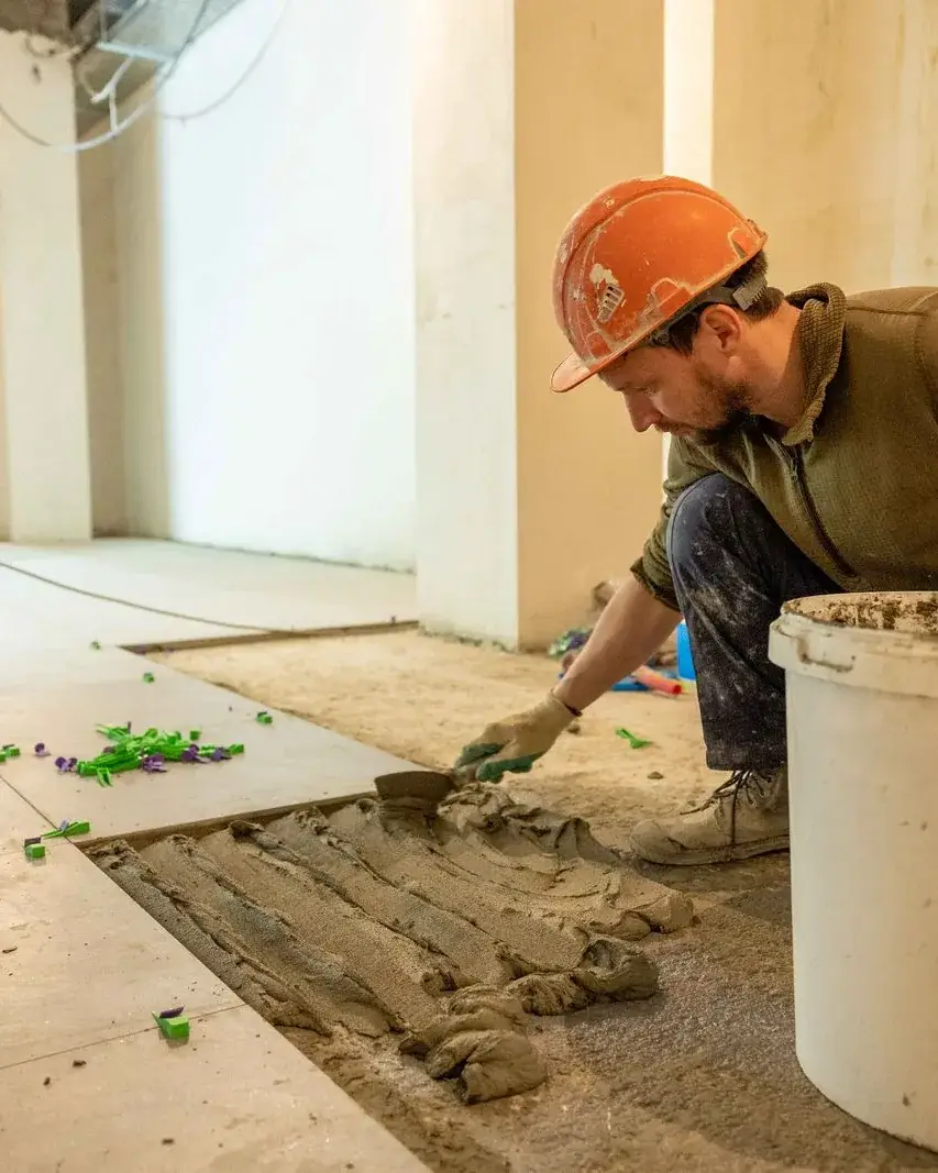 Worker laying floor tiles during a renovation