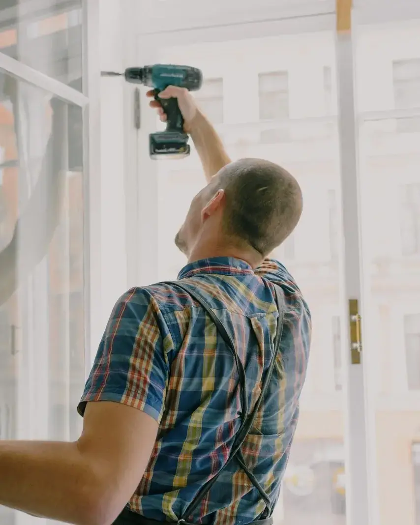Handyman fitting a window frame with a drill