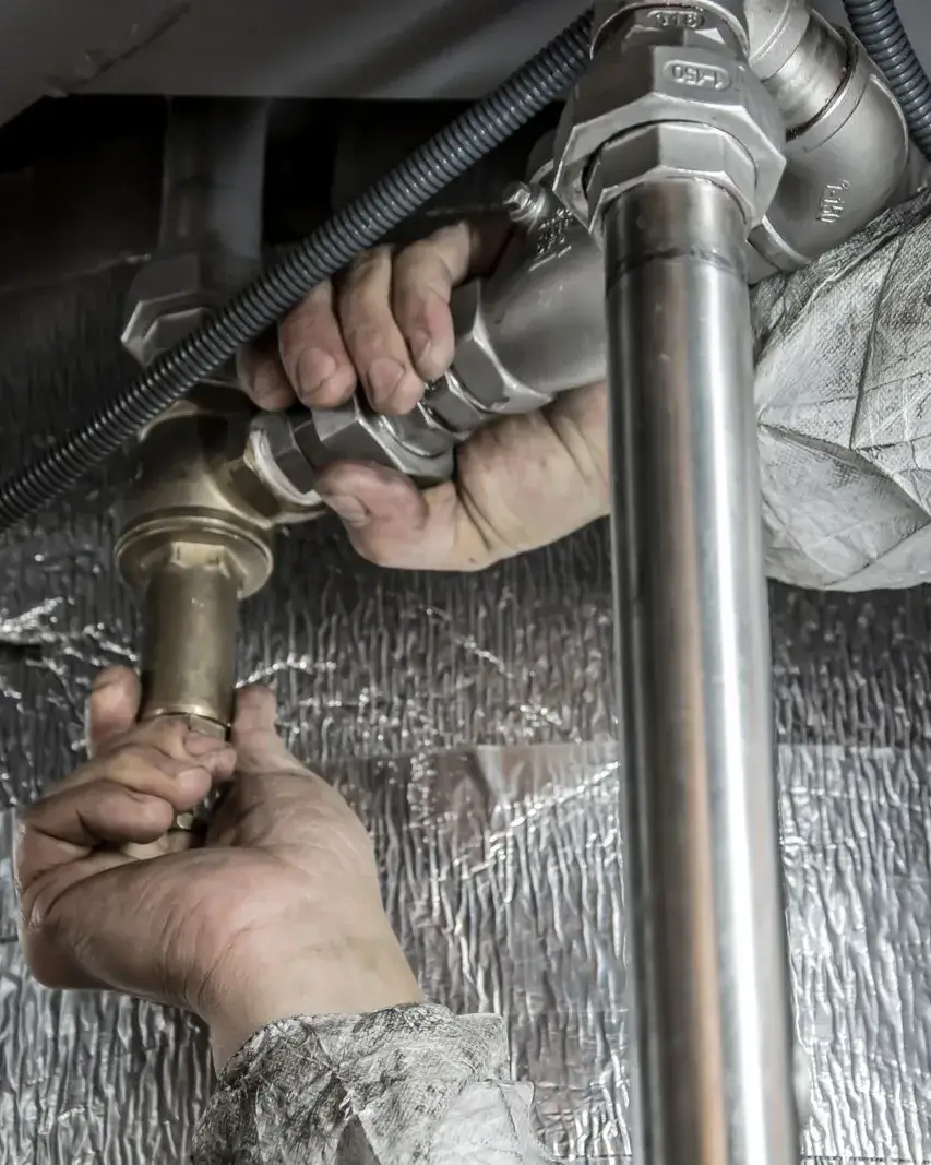 Plumber tightening a pipe fitting under a sink