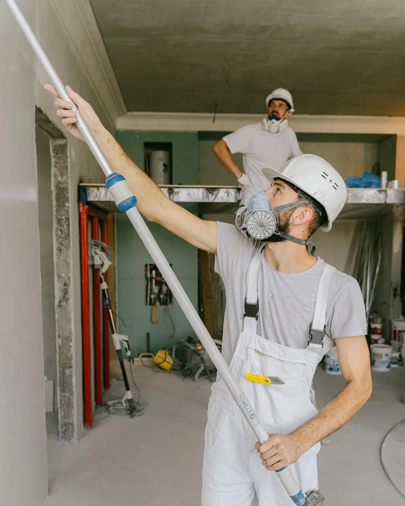 Two painters in overalls working in a room